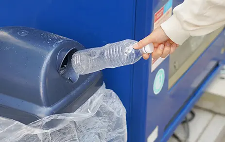 自動販売機にペットボトルを投入している様子